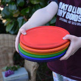 Grapat rainbow dishes stacked in a child's hands. 