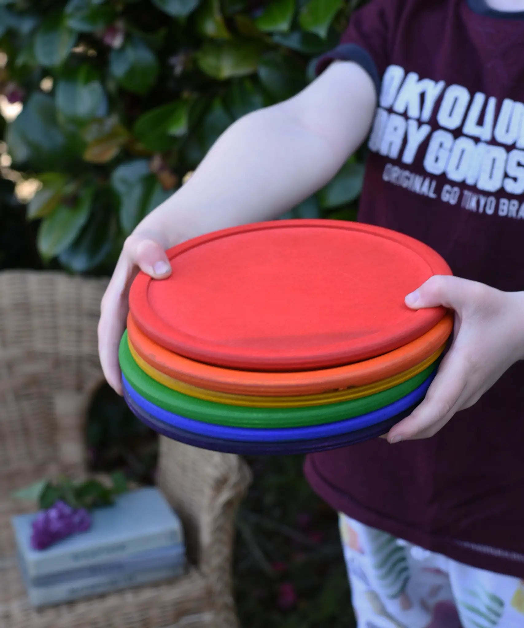 Grapat rainbow dishes stacked in a child's hands. 