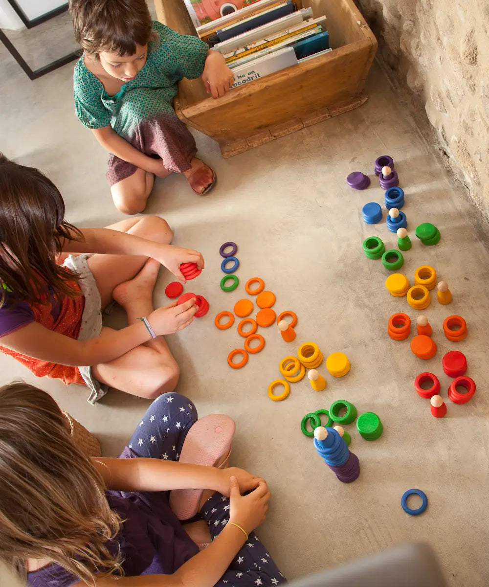 Children colour sorting with Grapat's handcrafted wooden disks, rings and coins on a concrete surface