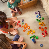 Children colour sorting with Grapat's handcrafted wooden disks, rings and coins on a concrete surface
