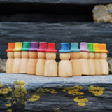 Grapat 12 Magos Rainbow Hats placed on slate. Natural wooden magos peg dolls with hand-painted rainbow coloured hats.