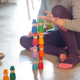 A close up of a child stacking the Grapat 12 Magos wooden peg dolls on top of each other. These wooden toys are part of a wide range of open ended toys available at Babipur.  