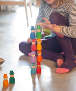A close up of a child stacking the Grapat 12 Magos wooden peg dolls on top of each other. These wooden toys are part of a wide range of open ended toys available at Babipur.  