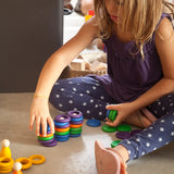 Child stacking Grapat handcrafted coloured wooden rings on a concrete surface 