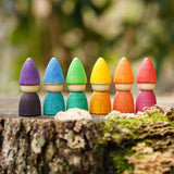 Grapat set of 6 Rainbow Tomten Figures placed on a tree stump outdoors. Grapat have a wide range of open ended wooden toys and loose parts available at Babipur. 