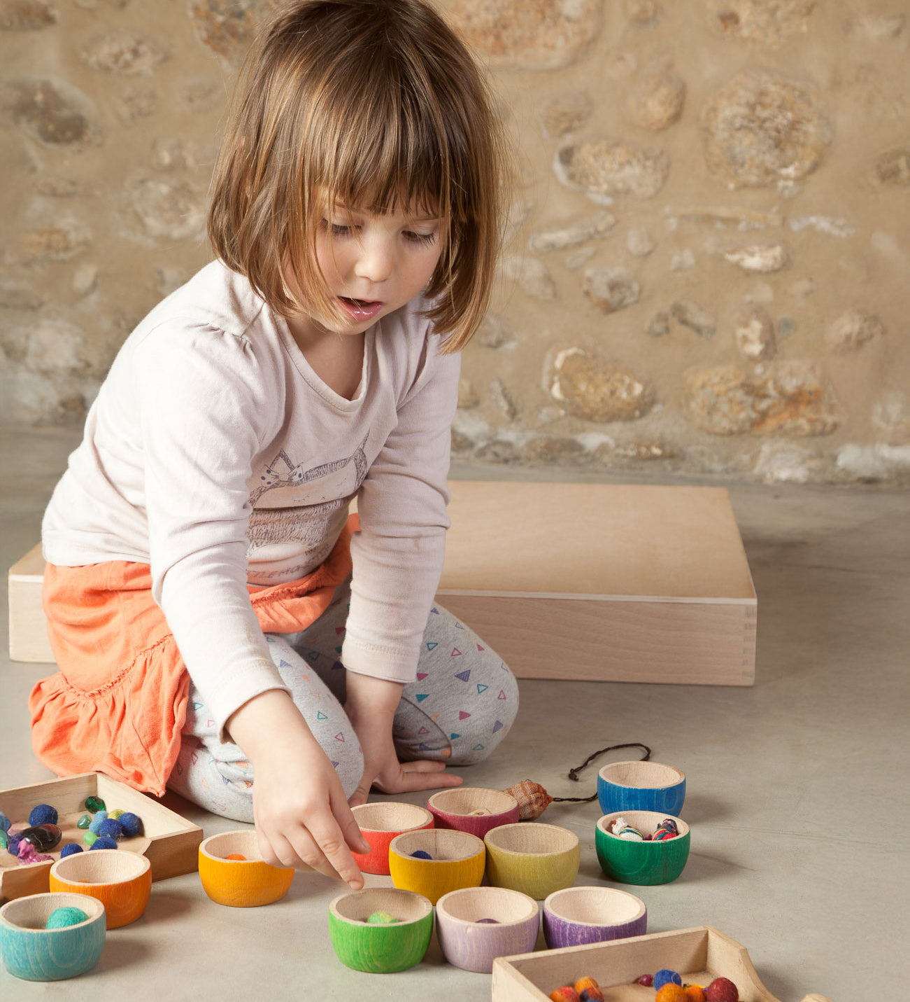 A child playing with the Grapat 12 Rainbow Wooden Sorting Bowls. These Grapat bowls are part of a big range of open ended wooden toys available at Babipur. 