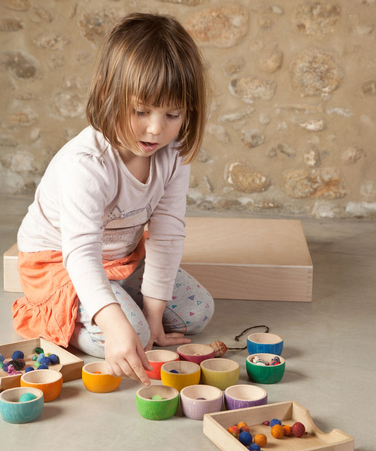 A child playing with the Grapat 12 Rainbow Wooden Sorting Bowls. These Grapat bowls are part of a big range of open ended wooden toys available at Babipur. 