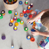 Child playing Grapat handcrafted coloured wooden rings and disks on a concrete surface 