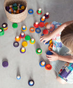 Child playing Grapat handcrafted coloured wooden rings and disks on a concrete surface 