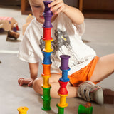 A child stacking the Grapat 18 Wooden rainbow coloured Spools on top of each other. These wooden toys are part of a wide range of open ended toys available at Babipur.  