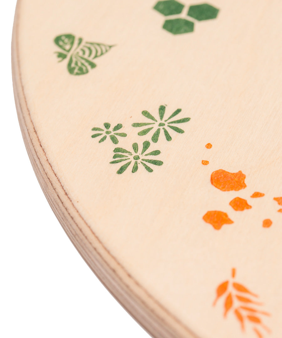 A close up of the green details on the Grapat 4 Seasons and Elements Play Platform. A wooden circle shaped platform and stamped with elements and details to represent the four season. These handcrafted items from Grapat are part of a wide range of wooden toys available here at Babipur.
