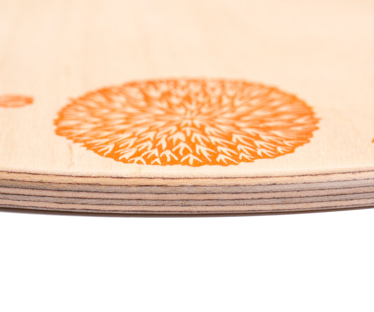 A close up of the orange details on the Grapat 4 Seasons and Elements Play Platform. A wooden circle shaped platform and stamped with elements and details to represent the four season. These handcrafted items from Grapat are part of a wide range of wooden toys available here at Babipur.