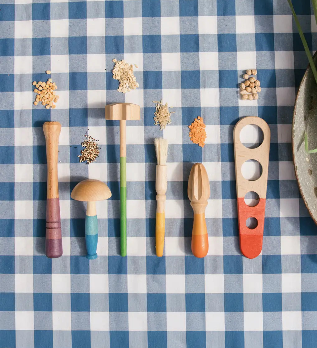 Grapat Sensory Play Tools wooden toy set. The play tools are placed on a blue and white gingham tablecloth.