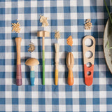 Grapat Sensory Play Tools wooden toy set. The play tools are placed on a blue and white gingham tablecloth.