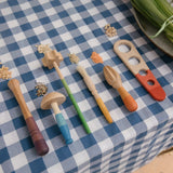 Grapat Sensory Play Tools wooden toy set. The play tools are placed on a blue and white gingham tablecloth.