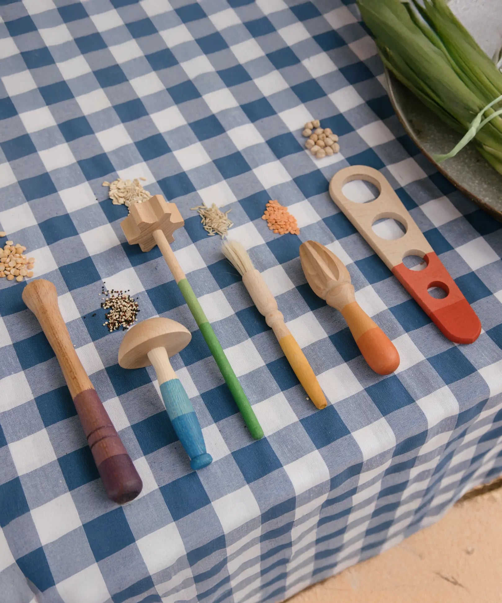Grapat Sensory Play Tools wooden toy set. The play tools are placed on a blue and white gingham tablecloth.