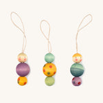 Multicoloured wooden Grapat snow buddy decorations on a cream background.