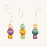 Multicoloured wooden Grapat snow buddy decorations on a cream background.
