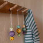 A wooden snow buddy wooden Grapat decoration hanging on a wooden hook.