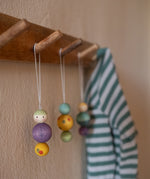 A wooden snow buddy wooden Grapat decoration hanging on a wooden hook.