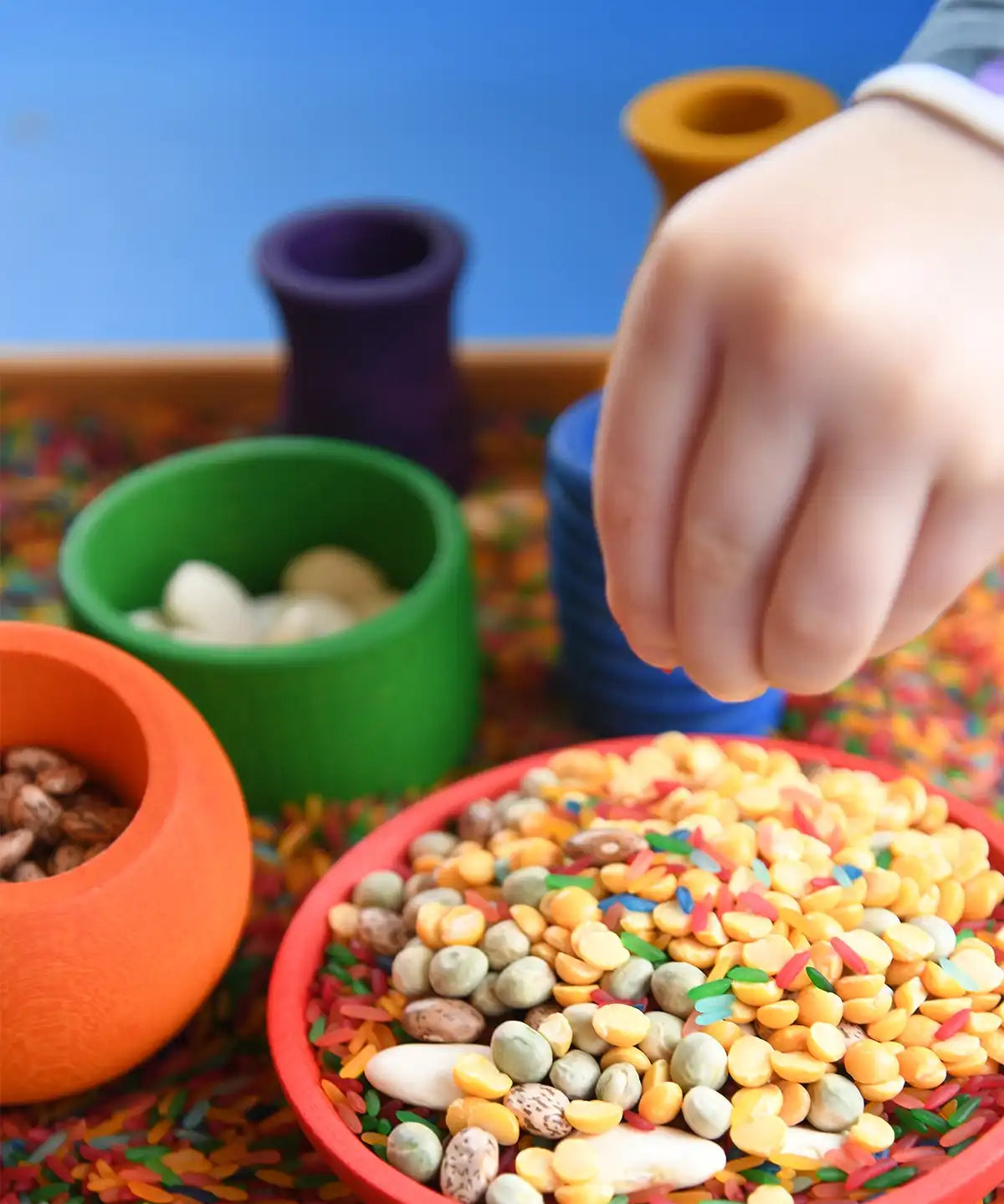 Close up of child's hand playing eith the Grapat sorting pots.
