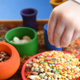Close up of child's hand playing eith the Grapat sorting pots.