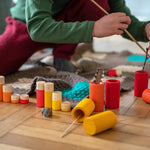 Close up of child playing with some sticks and the Grapat Waldorf wooden Lo toy figures