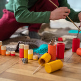 Close up of child playing with some sticks and the Grapat Waldorf wooden Lo toy figures