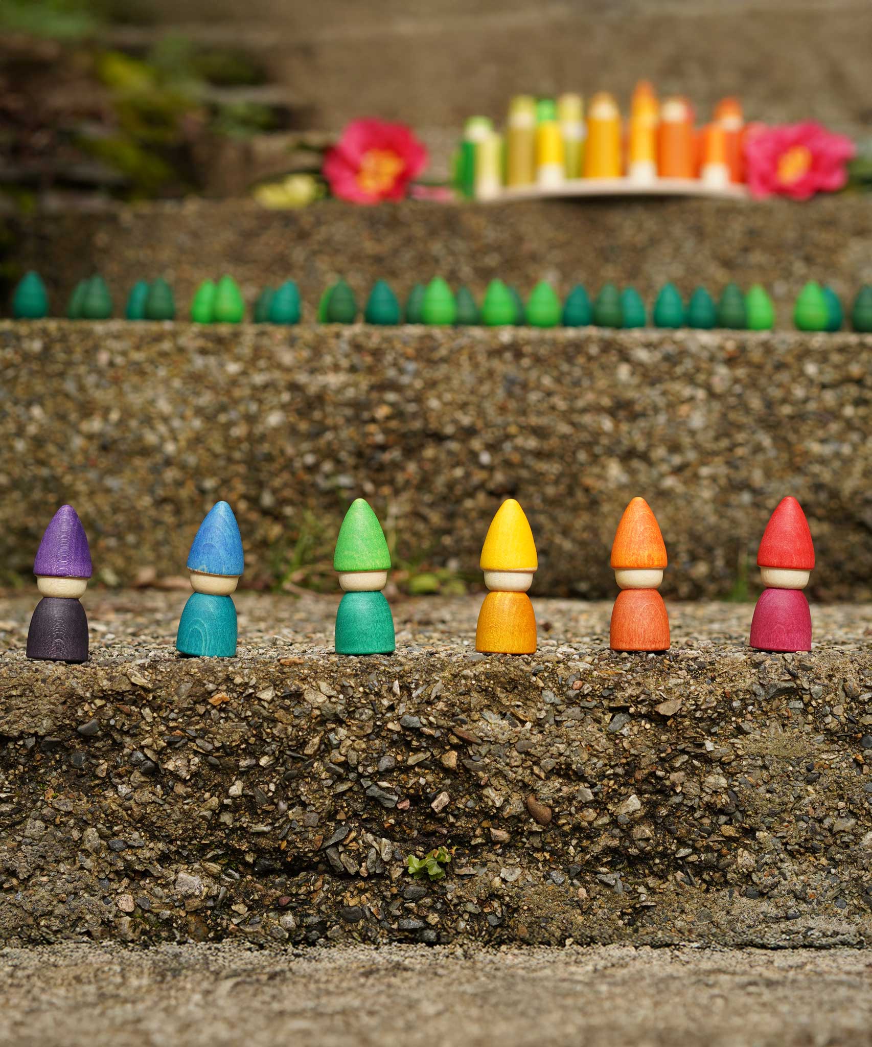 The Grapat set of 6 Rainbow Tomten Figures placed on a step outdoors. Grapat have a wide range of open ended wooden toys and loose parts available at Babipur. 