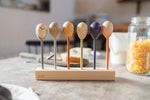 Grapat handcrafted and painted wooden twin soul puppets on a wooden stand next a jar or cereal on a kitchen table. Features a little boy, wise woman, a sun, a fairy and a mischievous girl puppet. 
