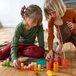 Two children playing with the Grapat plastic-free wooden lo tube set on a wooden floor