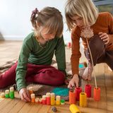 Two children playing with the Grapat plastic-free wooden lo tube set on a wooden floor