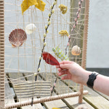 Child placing a red leaf into the Grapat weaving frame. 