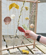 Child placing a red leaf into the Grapat weaving frame. 