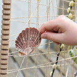 Child's hand placing a shell into the Grapat weaving frame.