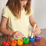A child playing with the Grapat Wooden Toy Bowls and  Acorns Set. A set of 6 coloured bowls with wooden acorn shapes in matching pieces. These wooden toys are part of a wide range of open ended toys available at Babipur.  