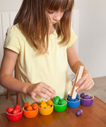 A child playing with the Grapat Wooden Toy Bowls and  Acorns Set. A set of 6 coloured bowls with wooden acorn shapes in matching pieces. These wooden toys are part of a wide range of open ended toys available at Babipur.  