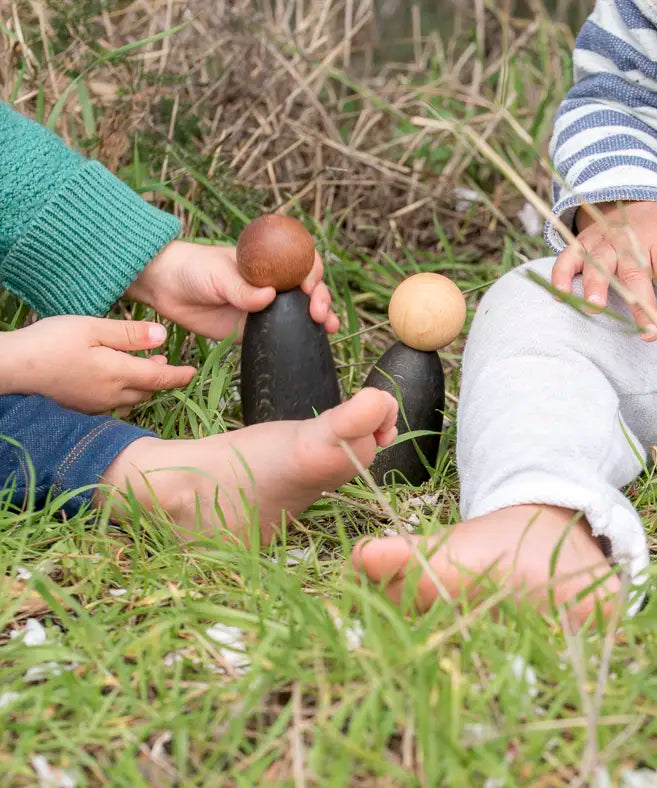 Children playing with Grapat waldorf adult wooden nin peg dolls on grass