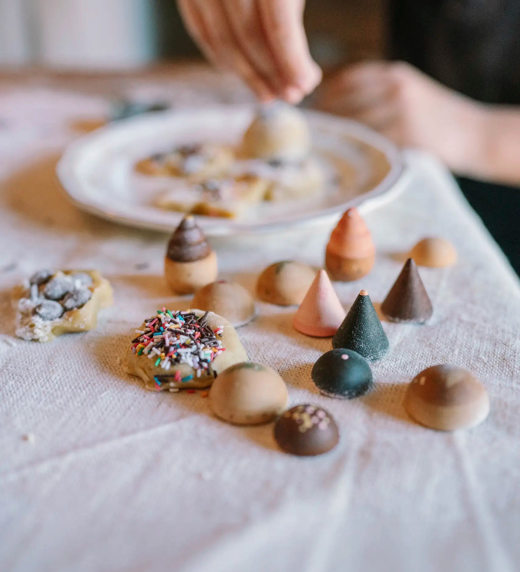Grapat bakes set showing different hand crafted wooden cake pieces on a table next to cookies and a child in the background