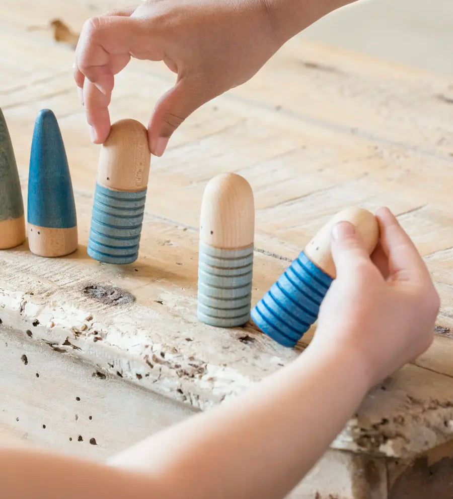 Children picking up blue Grapat wooden han crafted brot peg dolls