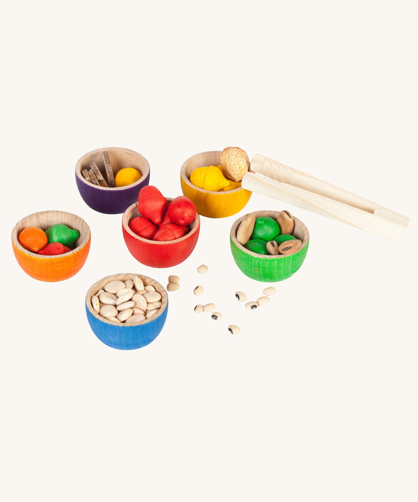 The Grapat Wooden Toy Bowls and  Acorns Set filled with the acorn shapes and dried pulses and small slices of wood. A set of 6 coloured bowls with wooden acorn shapes in matching pieces. These wooden toys are part of a wide range of open ended toys available at Babipur. 