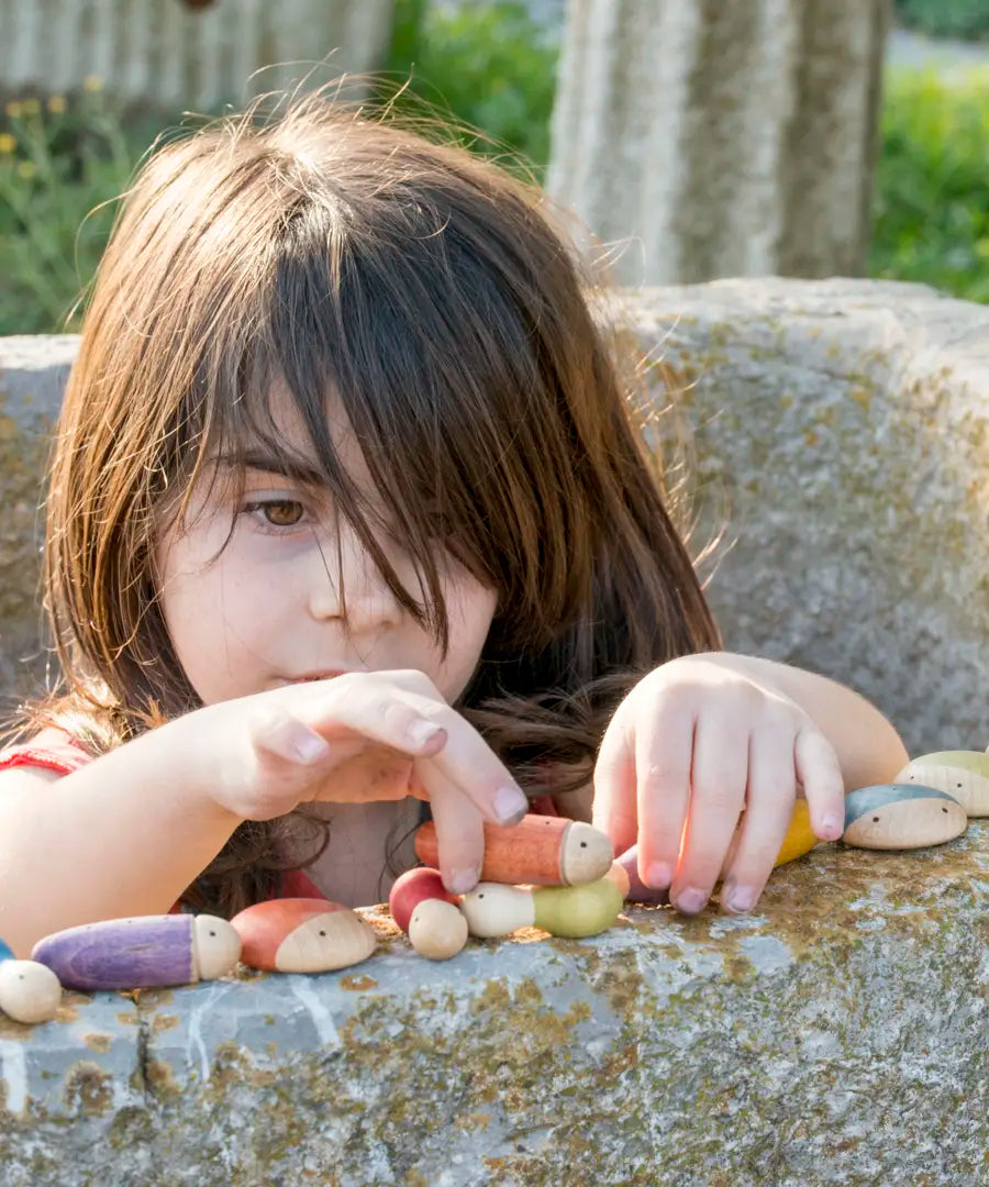 Child stacking different long Grapat insect pieces on a concrete wall