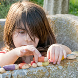 Child stacking different long Grapat insect pieces on a concrete wall