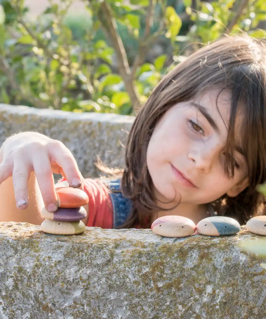 Child stacking different flat Grapat insect pieces on a concrete wall