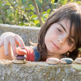 Child stacking different flat Grapat insect pieces on a concrete wall