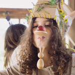 A child with a wooden spoon on their mouth with the bunny decoration looped on the handle. 