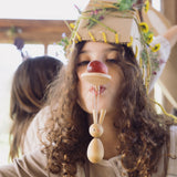 A child with a wooden spoon on their mouth with the bunny decoration looped on the handle. 