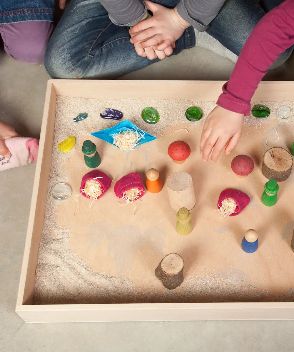 Children playing with a sensory small world using the Grapat freeplay tray, peg dolls and various small pieces