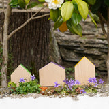 3 Grapat handcrafted wooden house shaped blocks with coloured roofs standing on a stone wall