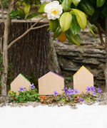 3 Grapat handcrafted wooden house shaped blocks with coloured roofs standing on a stone wall